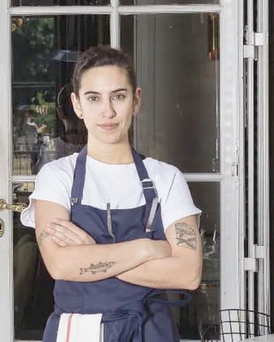 Catalina Rodríguez Triana con delantal, de brazos cruzados, en la puerta de una cocina